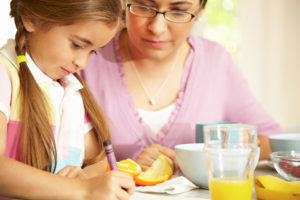 mother and daughter coloring near orange juice