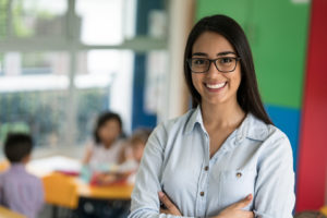 teacher smiling with long black hair and glasses
