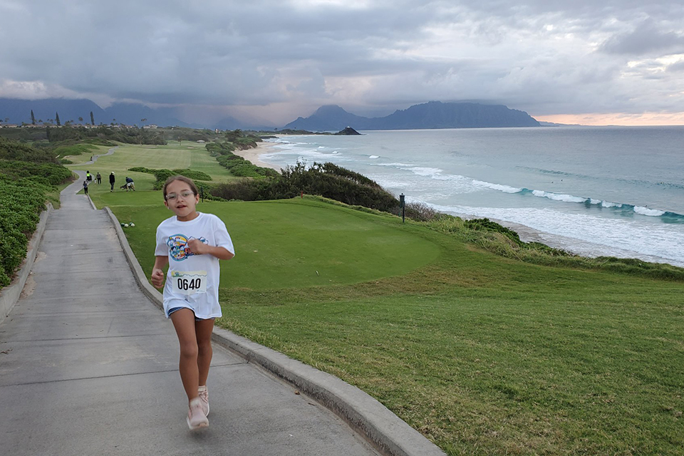 girl running on paved path along seaside in Hawaii