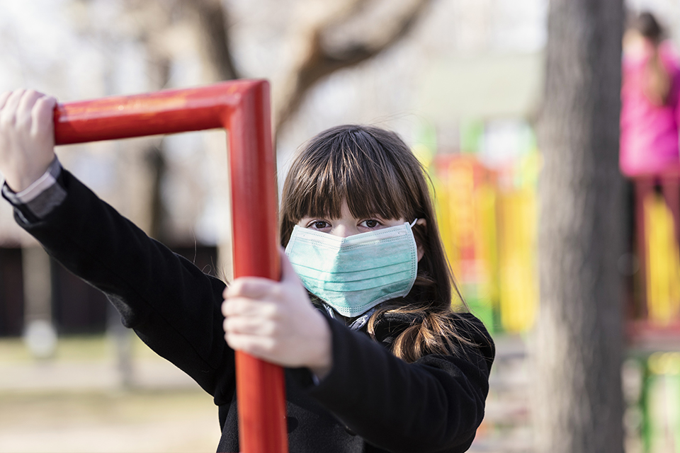 Young girl wearing surgical mask on playground