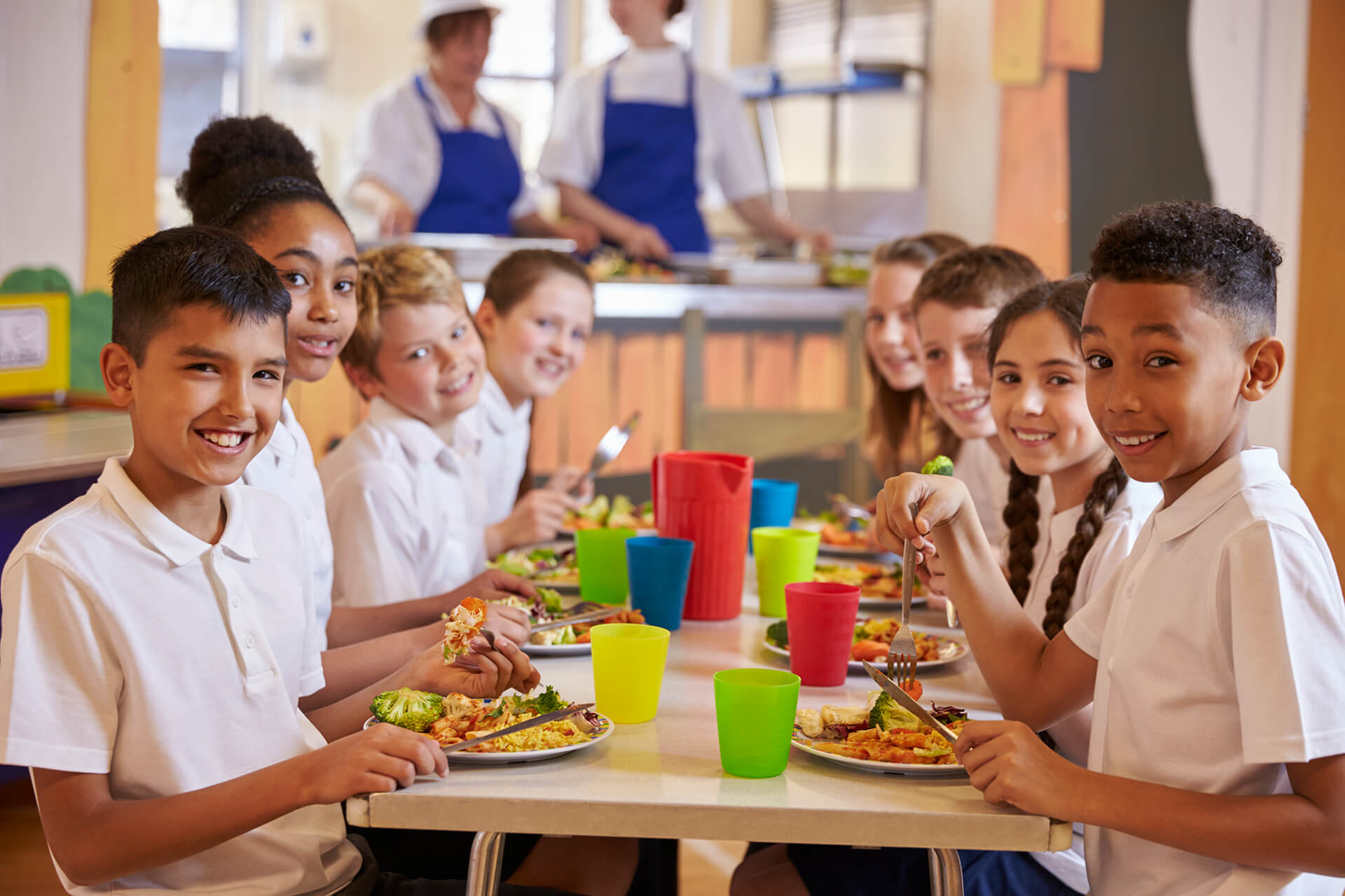Students eating healthy lunch at cafeteria table