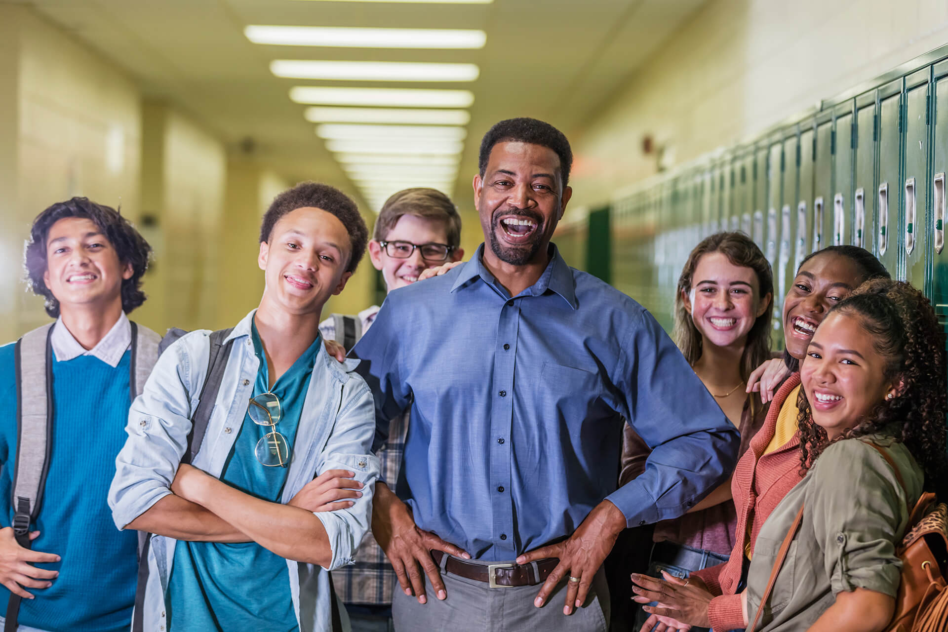 High school teacher and students standing in hallway smiling